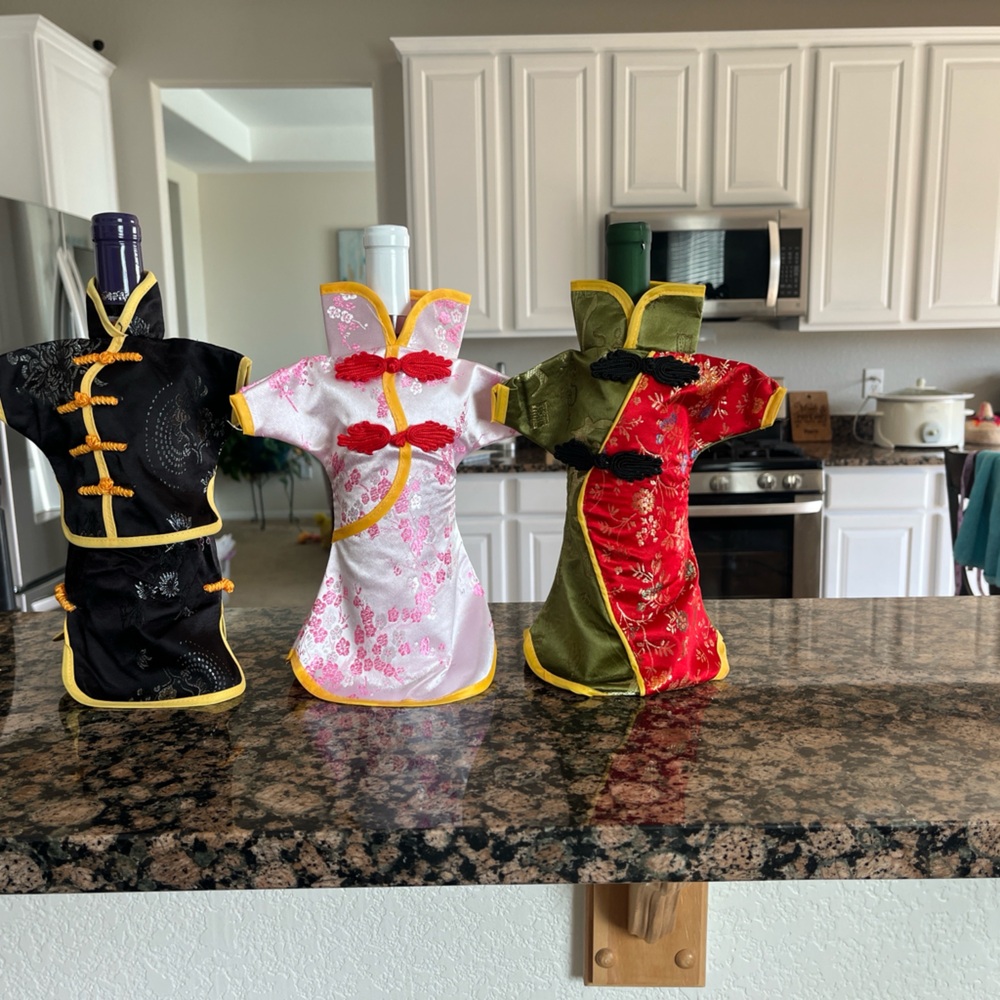 Set of three elegant wine bottle covers. Features intricate designs in black,